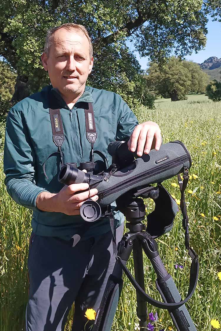 Hombre con equipo fotográfico en un paisaje verde.