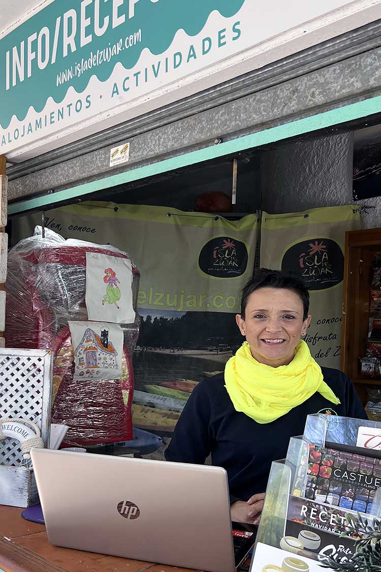 Mujer sonriente con pañuelo en el cuello amarillo dentro de un stand.