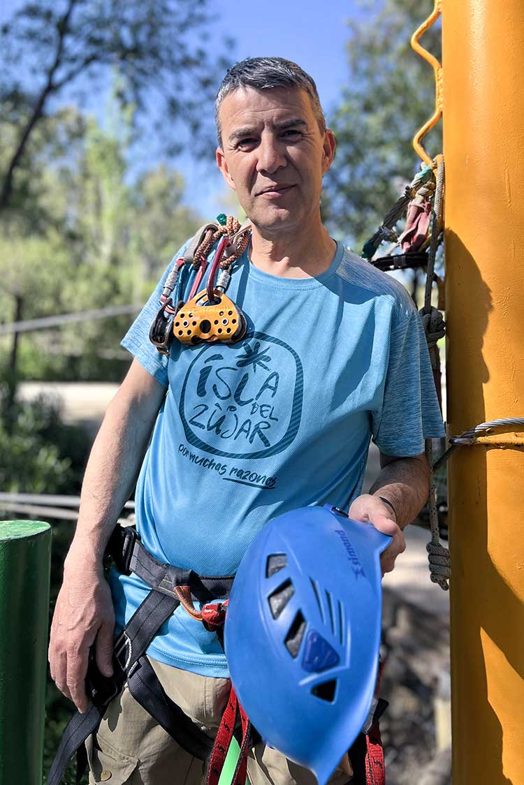 Hombre con casco de escalada y camiseta azul con letras Isla del Zújar.