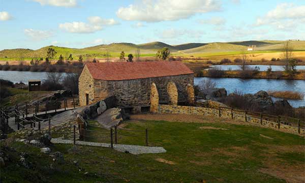 Casa de piedra en plena naturaleza rodeada de un lago.