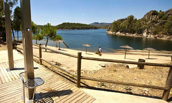 Plataforma de madera con vistas a una playa de arena de un amblase.