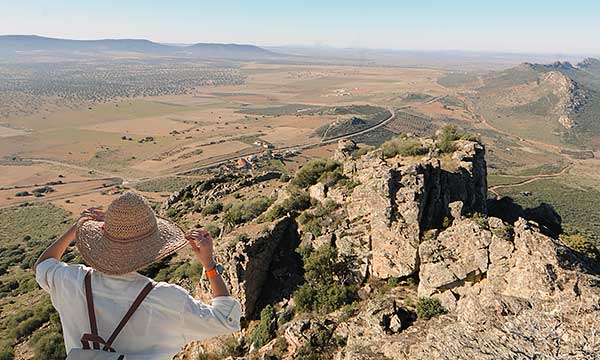 Mujer con sombrero en la cima de una montaña.